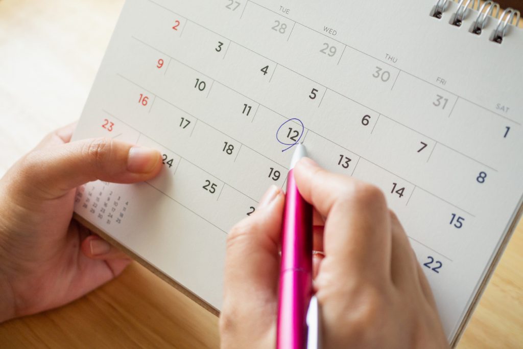 Mano de mujer señalando fecha en un calendario. Concepto: ¿Qué es un préstamo a plazos?