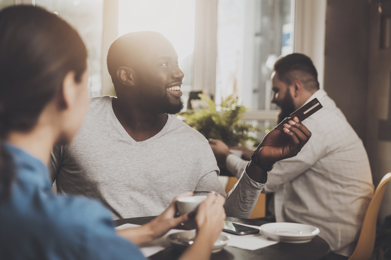 Young African American is calculated credit card. A smiling African American man is paying for an order in a cafe with a credit card. The concept of restaurant business and customer service. concept: Best Cashback Credit Cards