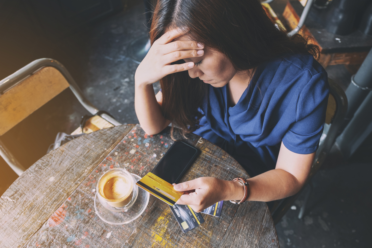 Stressed woman sitting at table with credit cards on it. Concept: How to get out of credit card debt.