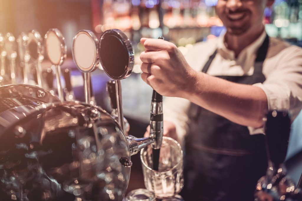 foto de un bartender alegre sirviendo bebidas y sonriendo. Concept: cómo abrir un bar