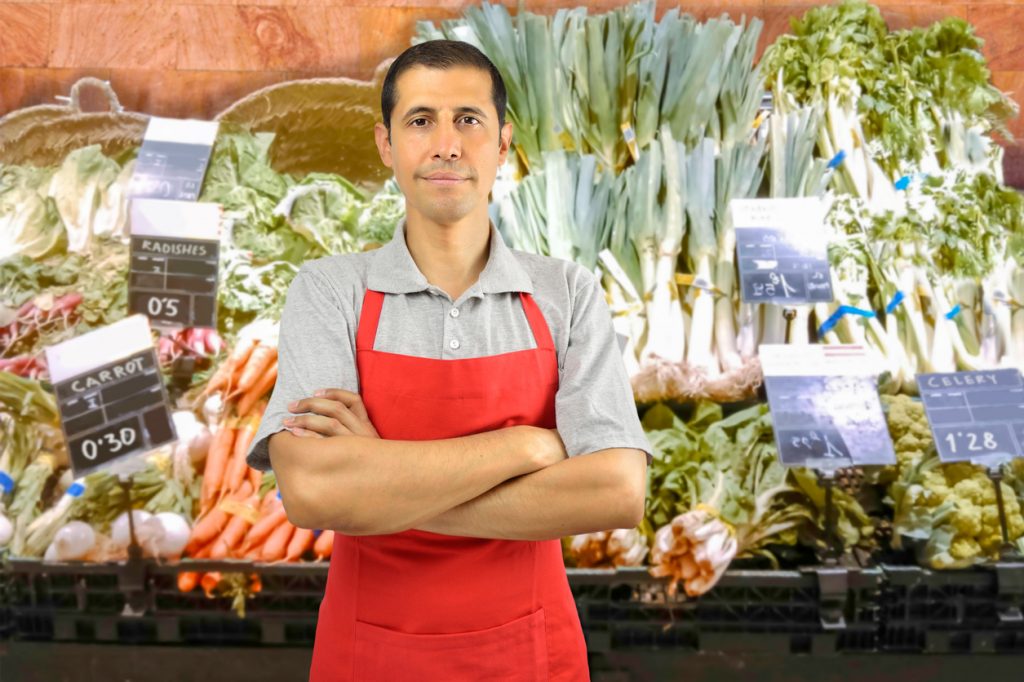 portrait of shopman at the vegetables store with crossing arms. Concept: FICA withholding