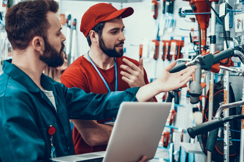 Dependiente y cliente comprando herramientas en tienda especializada. Concepto: Gastos variables.