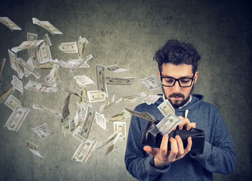 Sad man looking at his wallet with money dollar banknotes flying out away. Concept: prepayment penalty