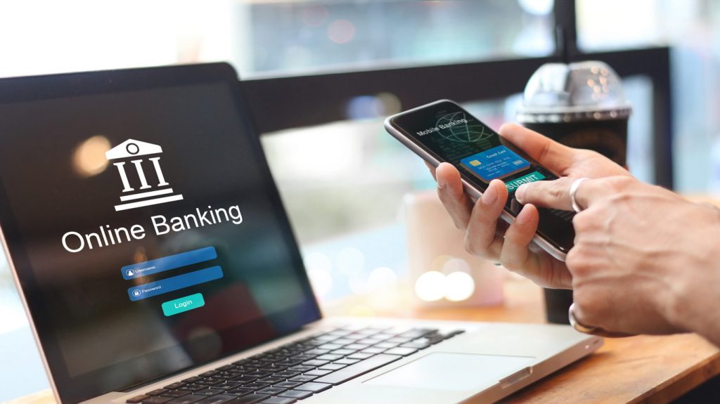 hombre usando banca en línea en su celular y su computadora. Concet: banca en línea