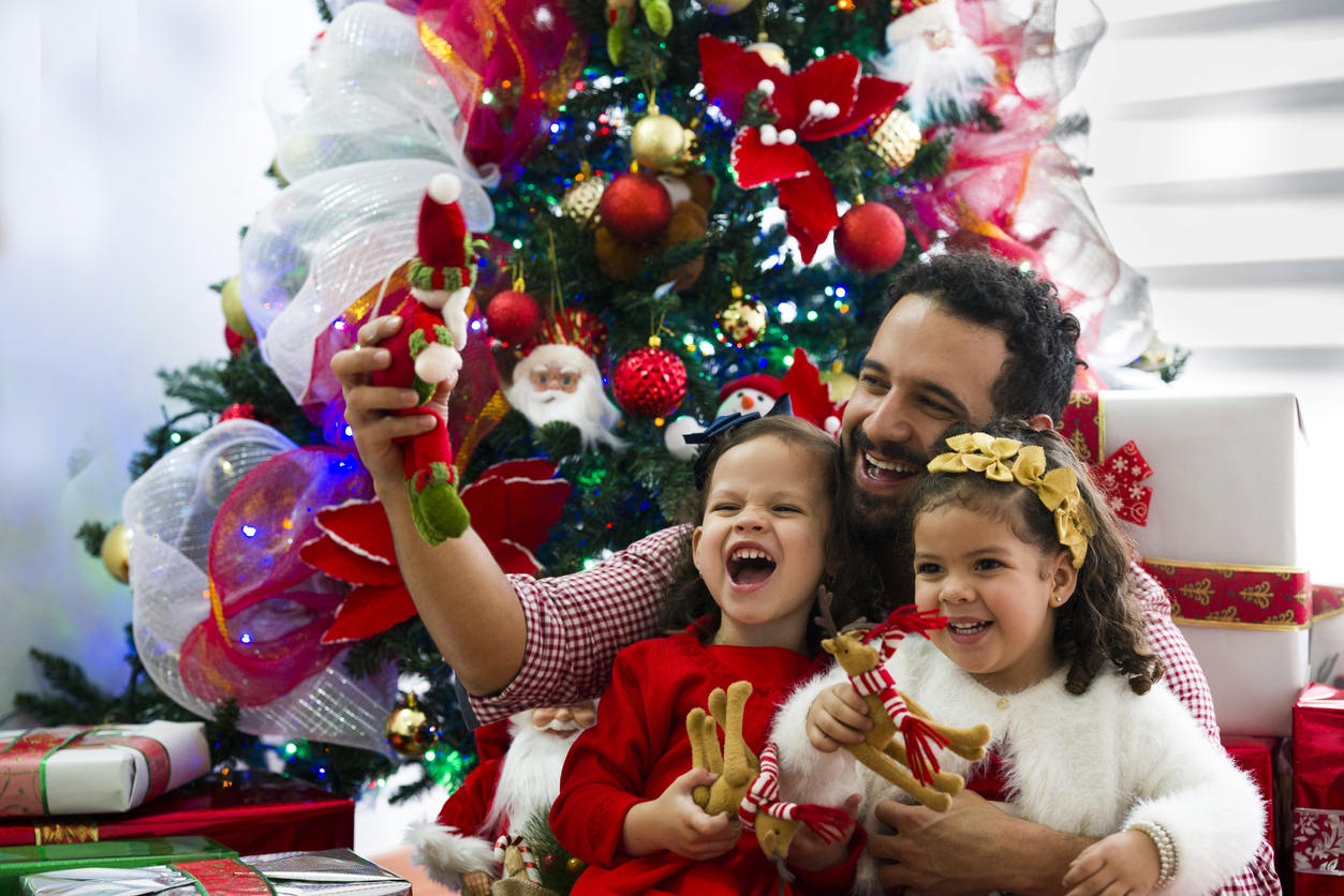 Dad and his two daughters, playing next to the Christmas tree. Concept: Family-work balance