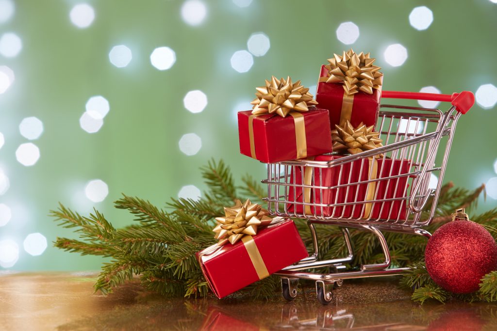 Carrito de compras con cajas de regalos y ramas de árbol navideño. concept: marketing