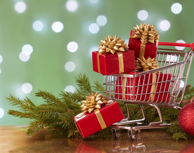 Carrito de compras con cajas de regalos y ramas de árbol navideño. concept: marketing