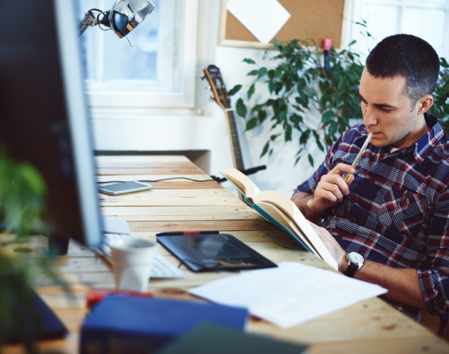 Hombre sentado en su oficina nleyendo un libro. concept: libros de marketing