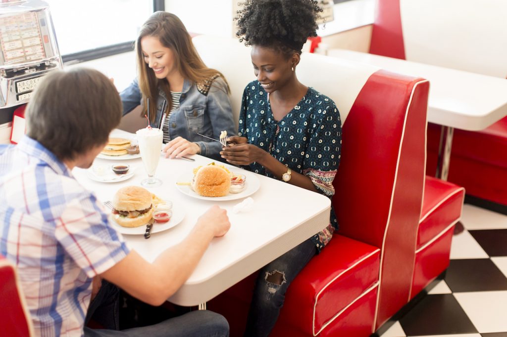 Amigos comiendo hamburguesas en una franquicia de restaurantes.