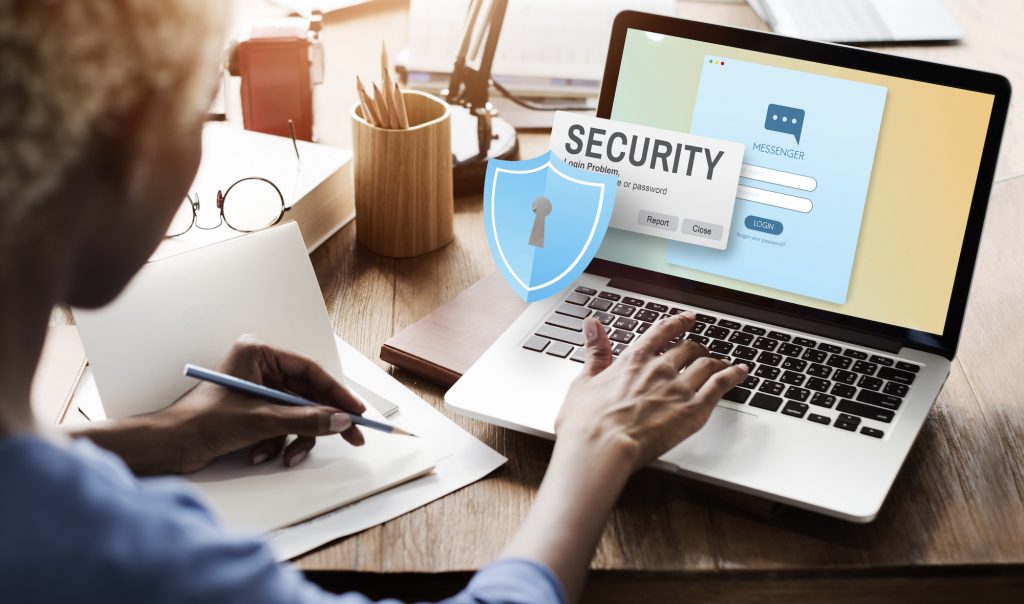 Woman at computer with cyber security icon on screen. Concept: cyber insurance providers.