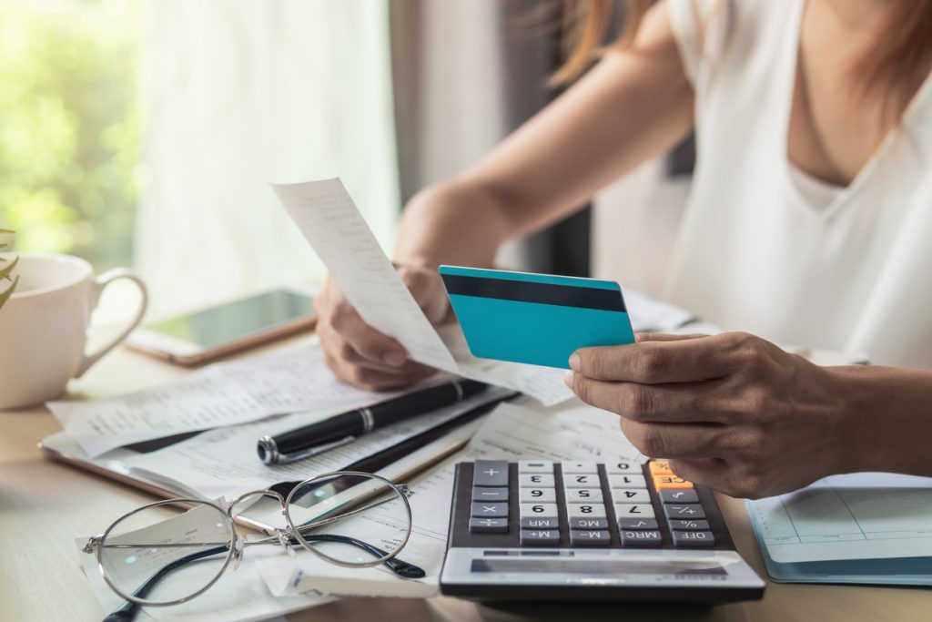 Mujer revisando sus cuentas del banco, haciendo cáluclos, tarjeta de crédito. Concept:Fórmula del costo de la deuda