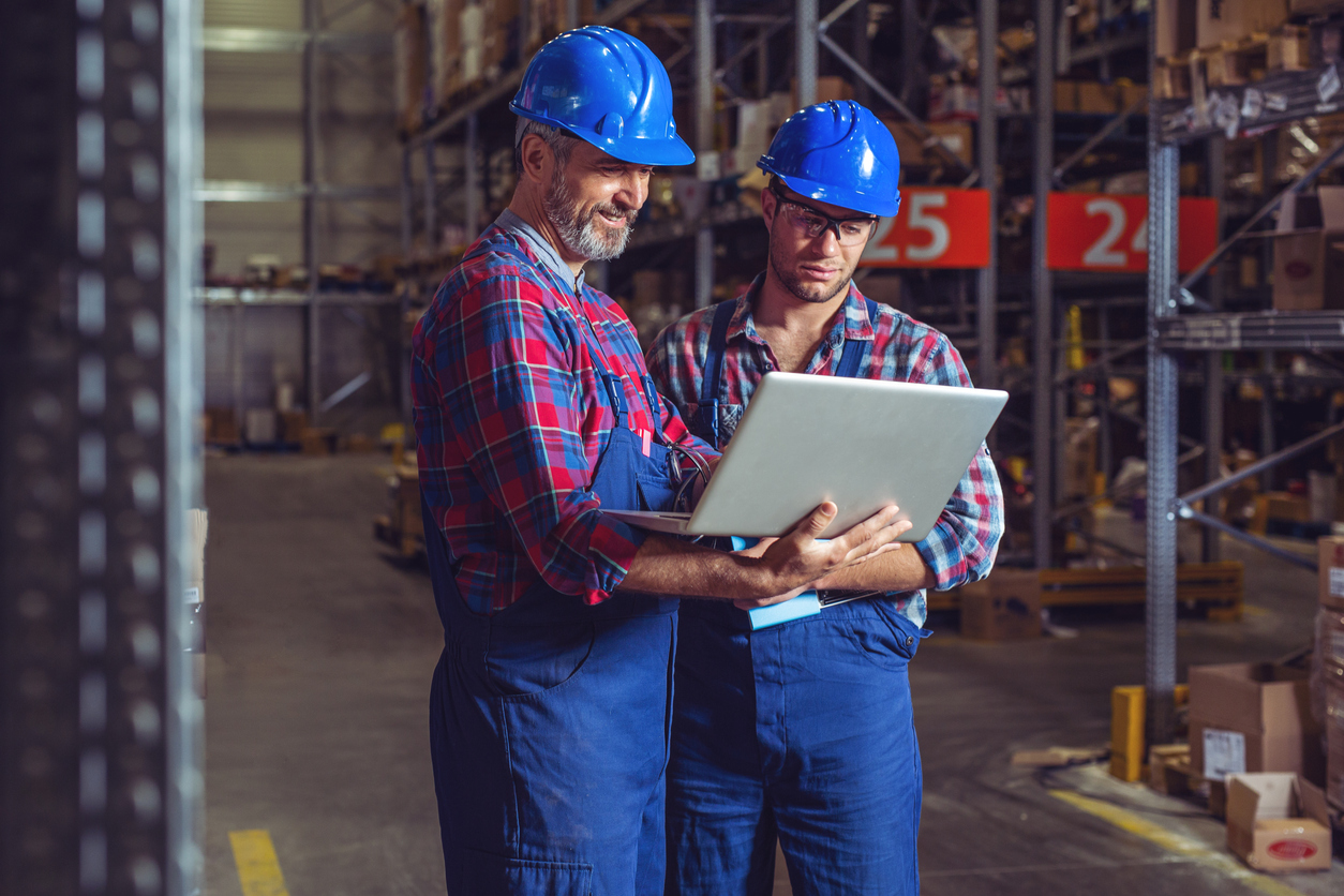 Two business owners in warehouse with laptop. Concept: Profitability ratios