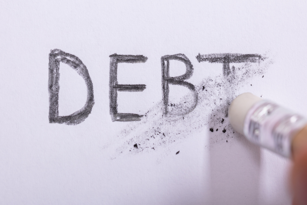 Close-up Of Pencil Eraser Erasing Debt Word On White Paper. concept: Charged Off Account