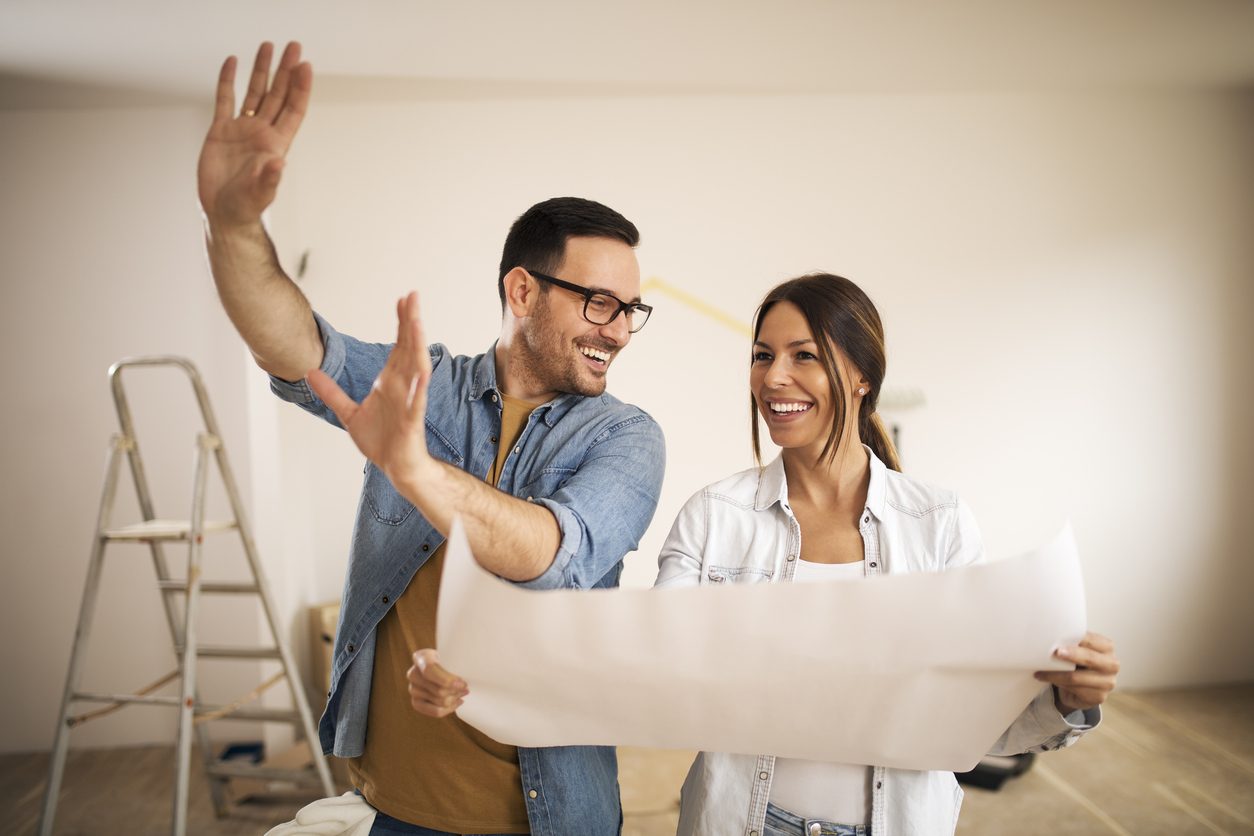 Young couple standing in their apartment while woman holding blueprint and man showing to her new ideas. Concept: personal loan