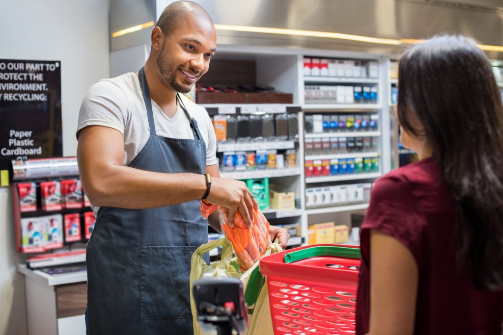 Polite cashier at shop attending customer at cashier. Concept: customer appreciation.
