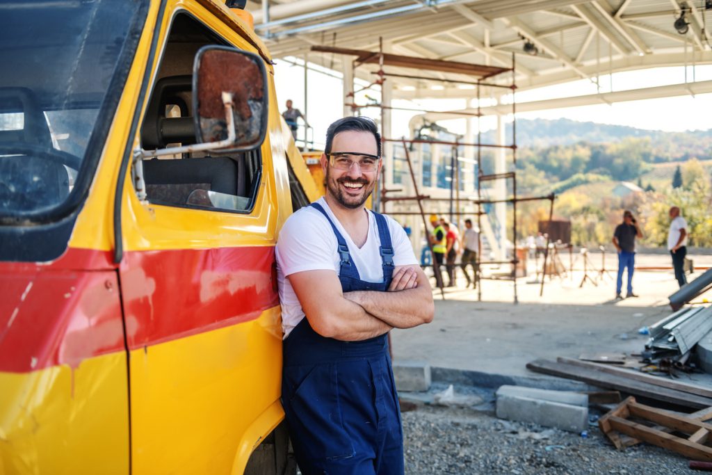 Worker leaning on company's truck and smiling to camera. Concept: Best auto loans for small businesses