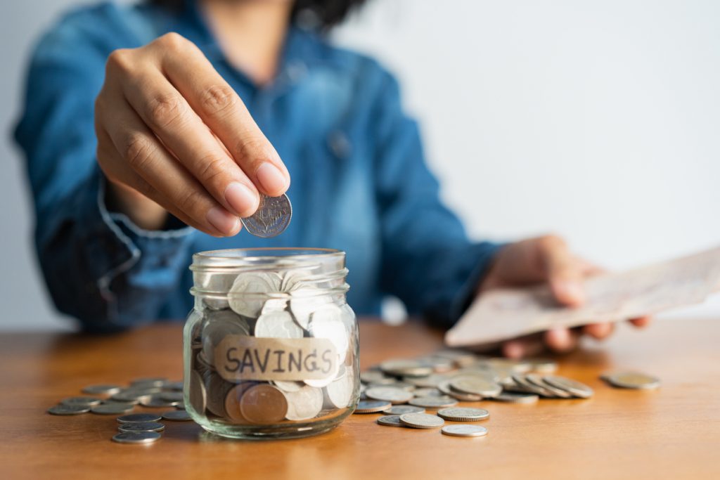 Mano poniendo dinero en un vaso con ahorros. concept: cuentas de ahorros