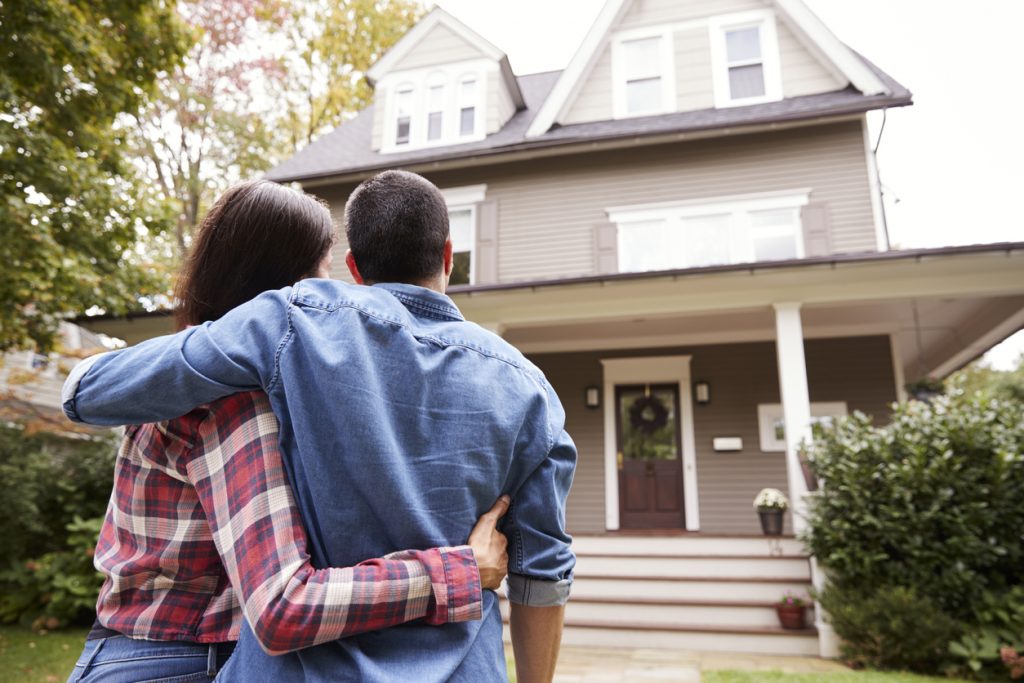 Rear View Of Loving Couple Looking At House. concept: Home Construction Loan