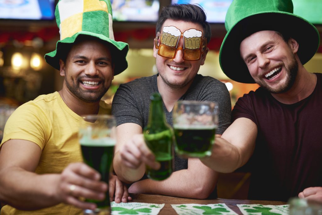 Tres amigos bebiendo cerveza verde en un pub el Día de St. Patrick.