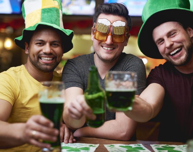 Tres amigos bebiendo cerveza verde en un pub el Día de St. Patrick.