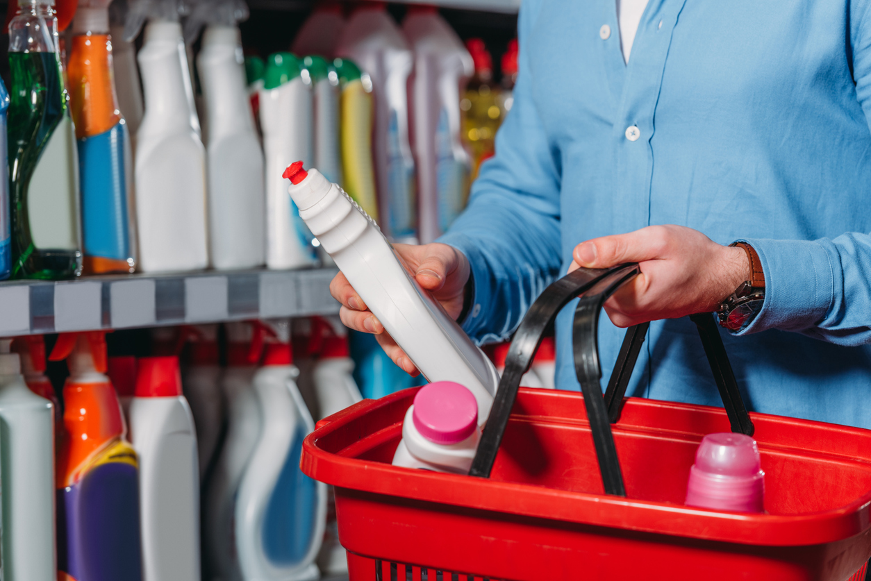 partial view of shopper putting detergent into shopping basket in supermarket. Concept:How to adjust your prices during a crisis