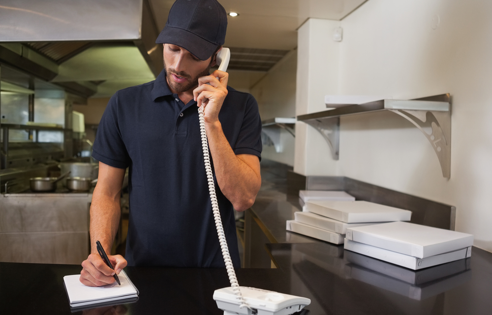 Pizza restaurant employee taking relivery rder over the telephone. Concept: Tips to keep your restaurant or bar in business during a health crisis