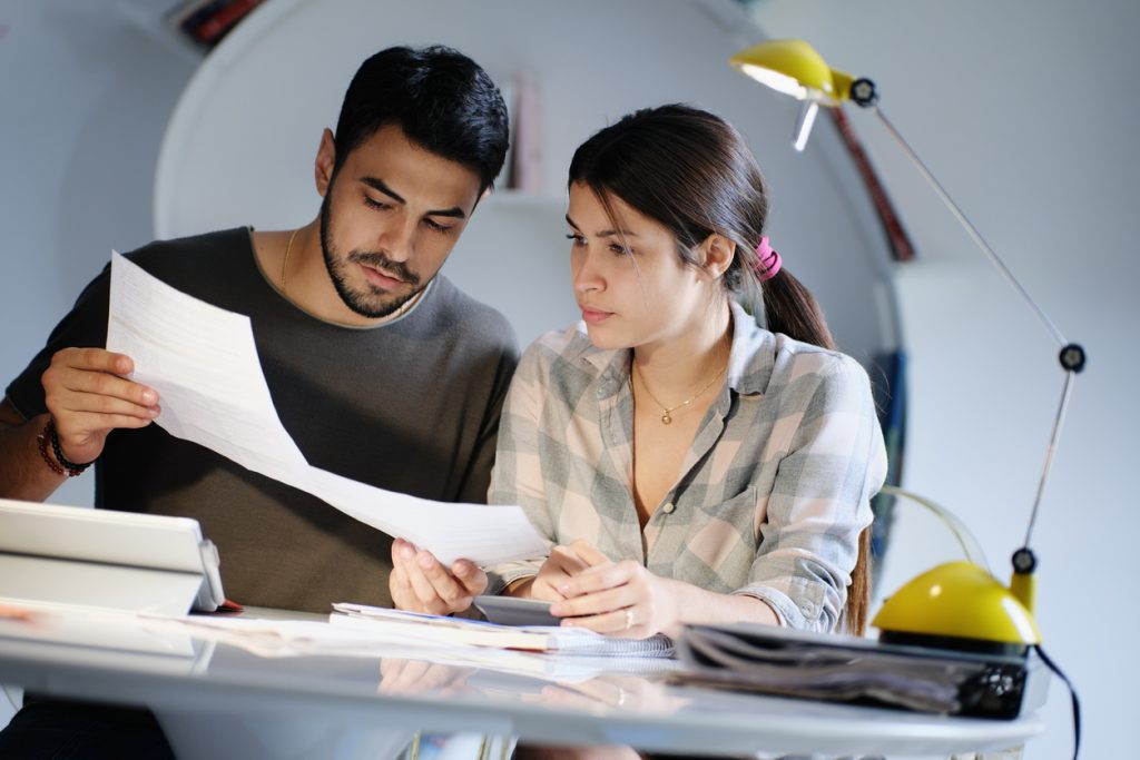 Young couple reviewing invoices and doing family business plan. Concept of money and economic problem for man and woman living together. concept: coronavirus stimulus