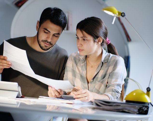 Pareja joven revisando estados bancarios e impuestos.