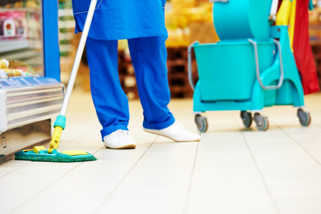 Female cleaner worker in uniform with mop cleaning the floor of supermarket shop store. concept: COVID-19 Best Practices