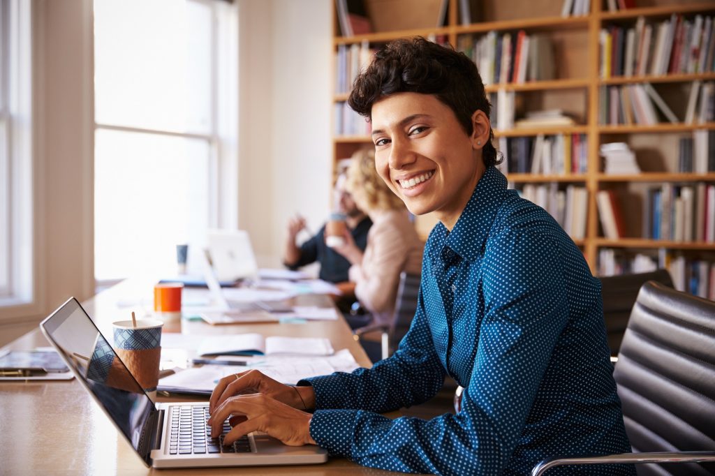 Mujer de negocios usando una computadora en su oficina. concept: Cómo mantenerse positivo durante el coronavirus