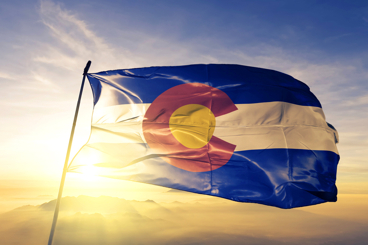 Colorado state of United States flag on flagpole textile cloth fabric waving on the top sunrise mist fog