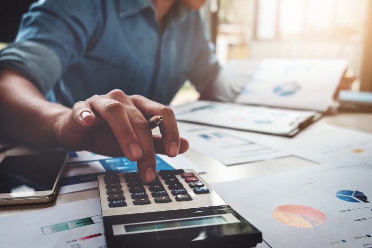 Business accounting concept, Business man using calculator with computer laptop, budget and loan paper in office. concept: Business Line of Credit Calculator