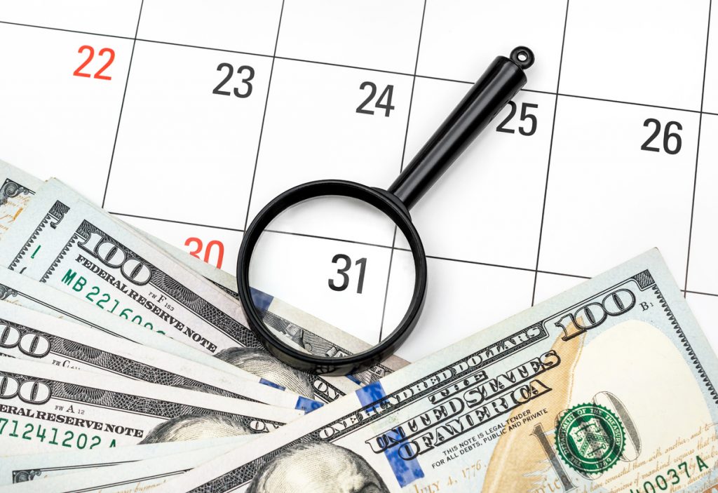 Lupa con dinero en calendario. Concept: pagos mensuales