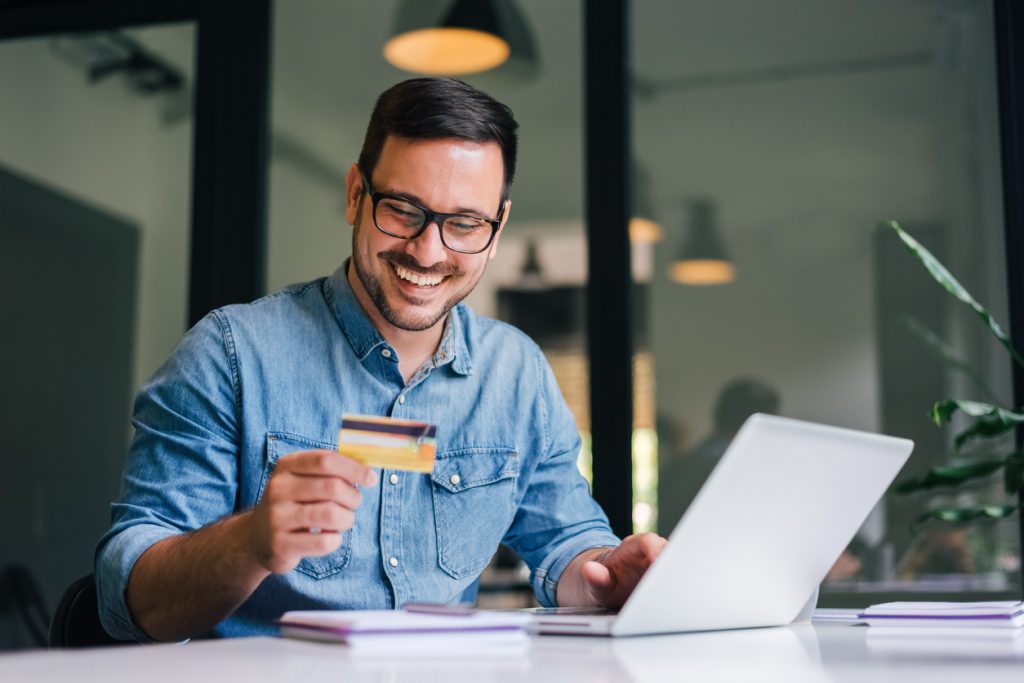 Empresario feliz mientras sostiene una tarjeta de crédito comercial