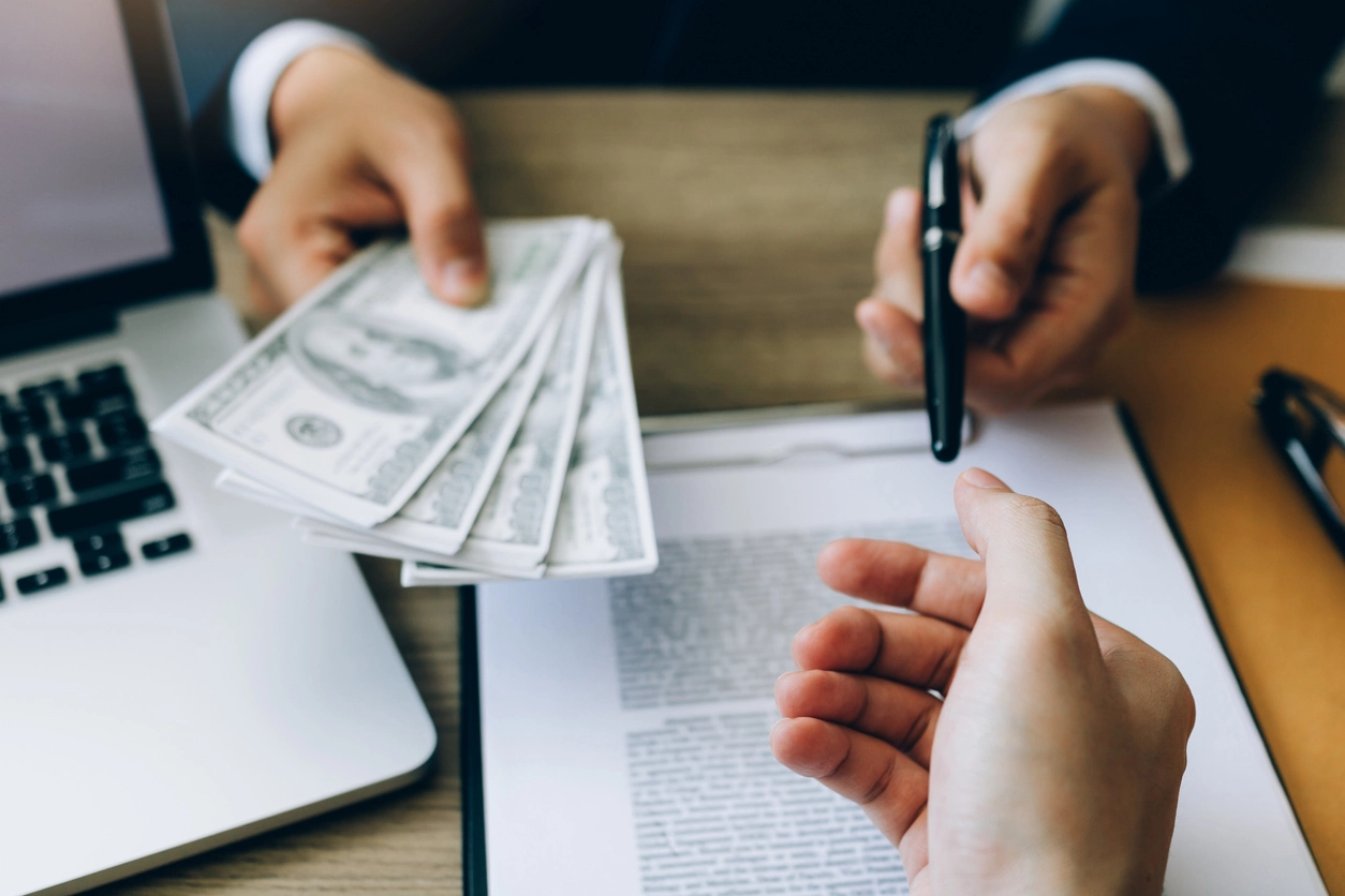 mano entregando dinero y contrato para firmar